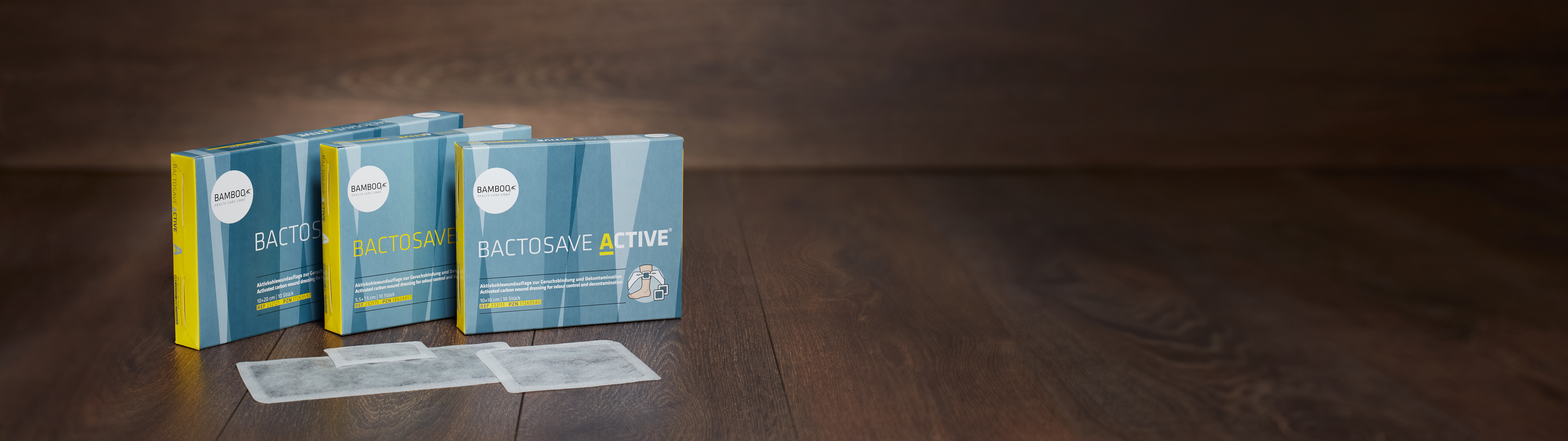 Die drei Verpackungsgrößen von BactoSave Active® stehend auf einem dunklen Holzboden. | © Bamboo Health Care GmbH