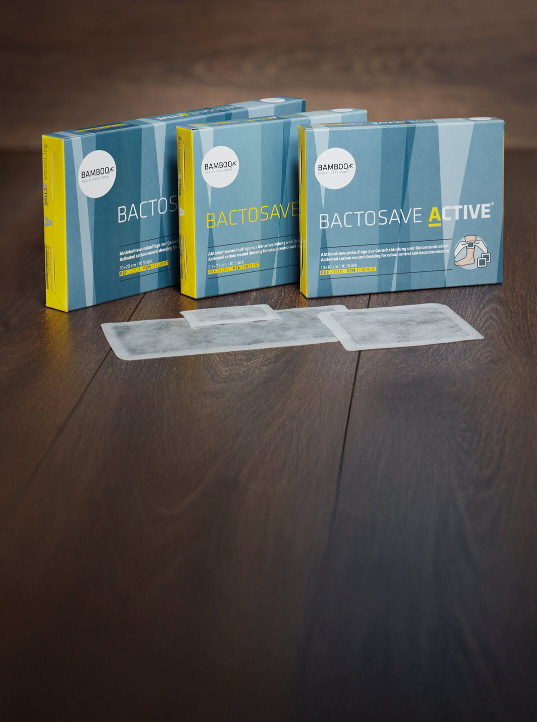 Die drei Verpackungsgrößen von BactoSave Active® stehend auf einem dunklen Holzboden. | © Bamboo Health Care GmbH