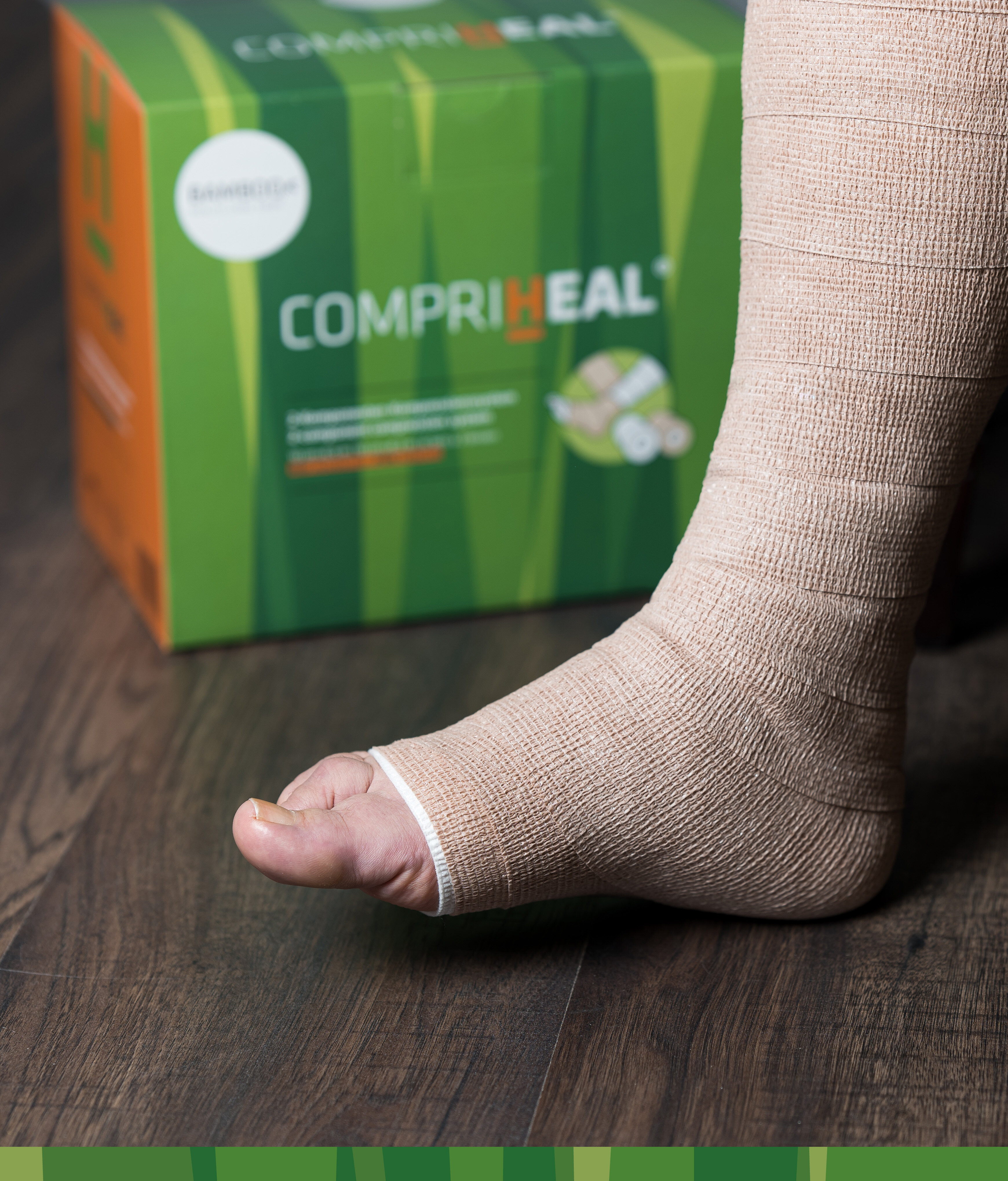 Fuß mit angewickeltem Compri-Heal® Kompressionsverband mit Verpackung im Hintergrund. | © Bamboo Health Care GmbH