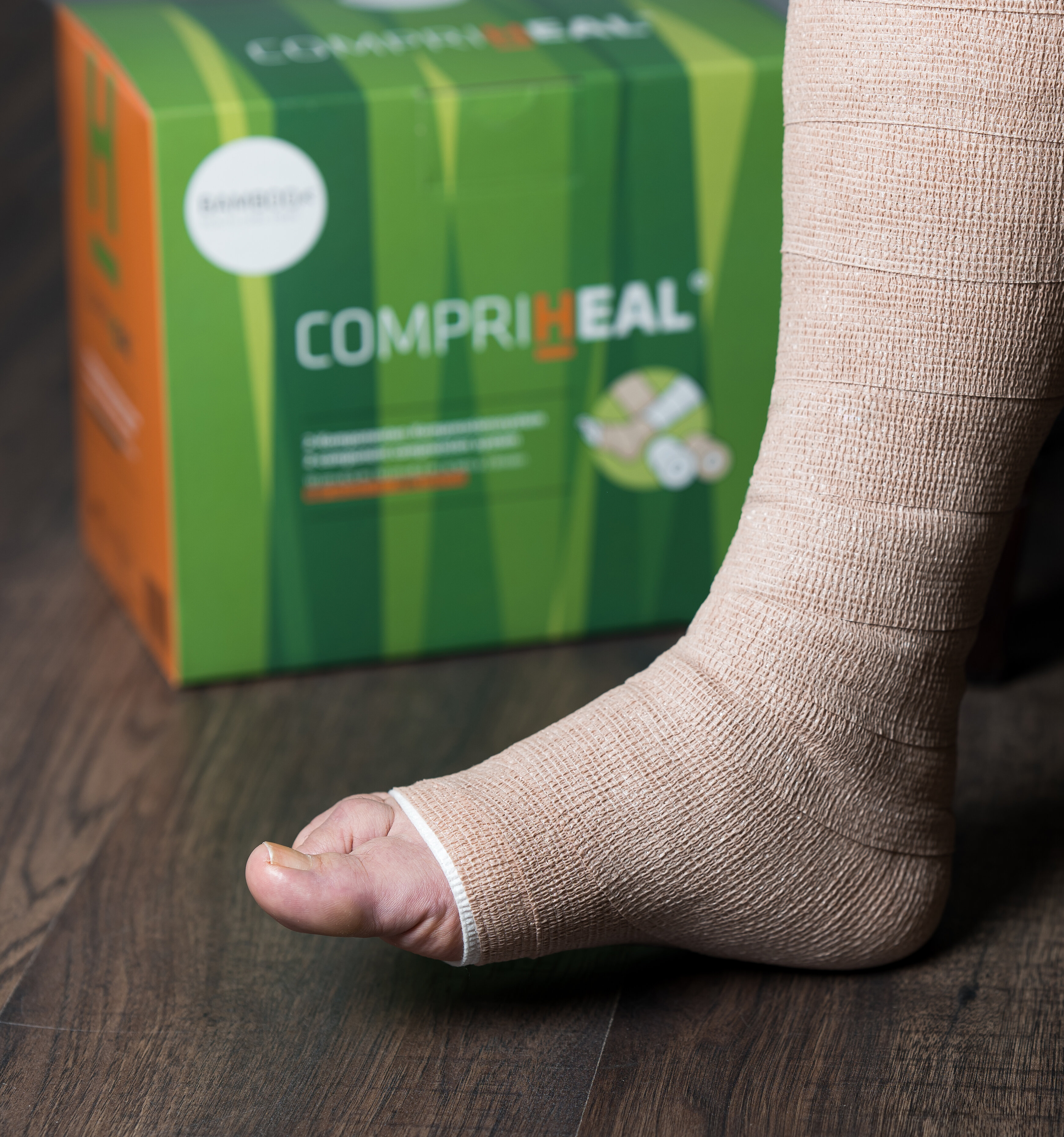 Fuß mit angewickeltem Compri-Heal® Kompressionsverband mit Verpackung im Hintergrund. | © Bamboo Health Care GmbH