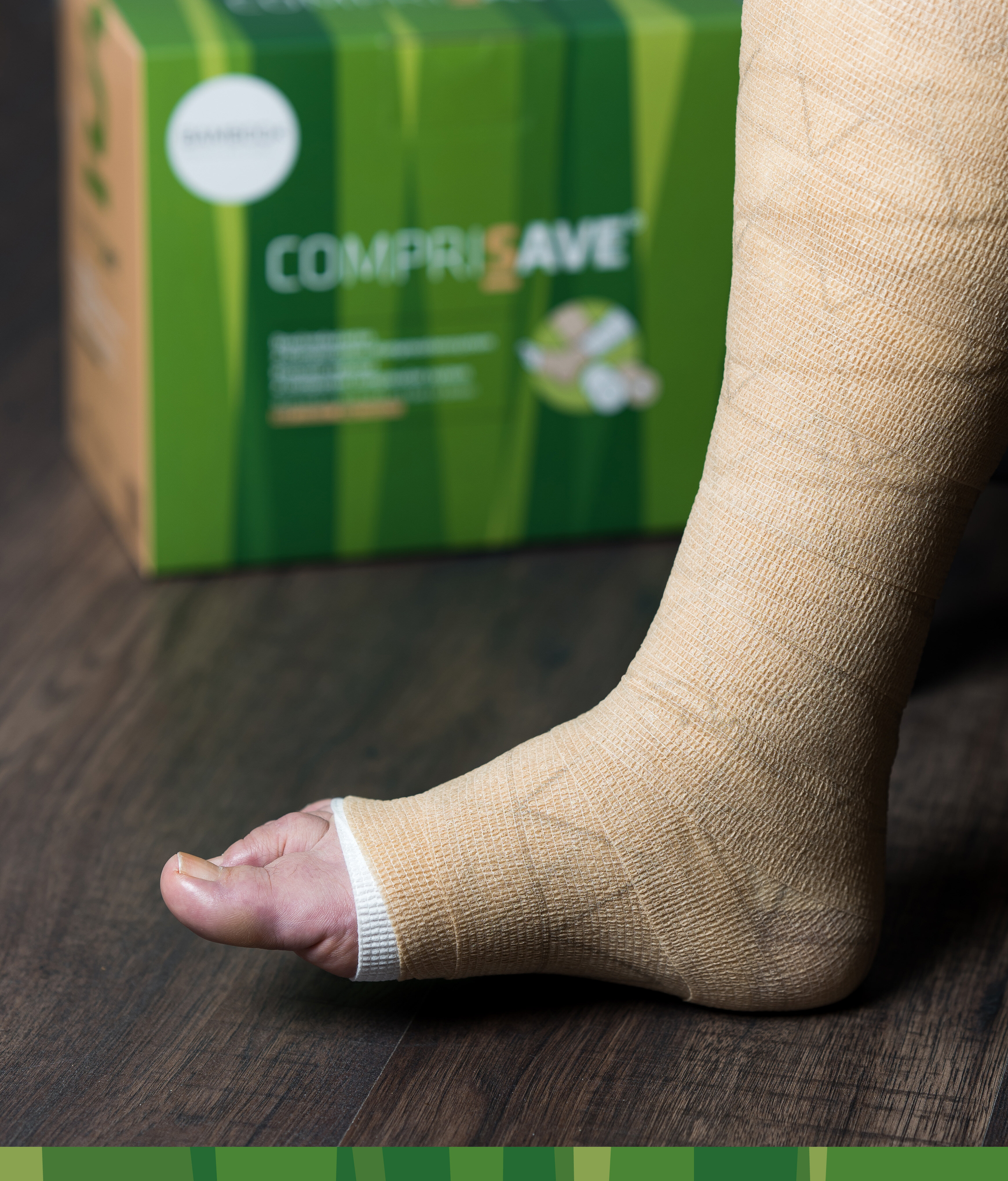 Fuß mit angewickeltem CompriSave® Kompressionsverband mit Verpackung im Hintergrund. | © Bamboo Health Care GmbH