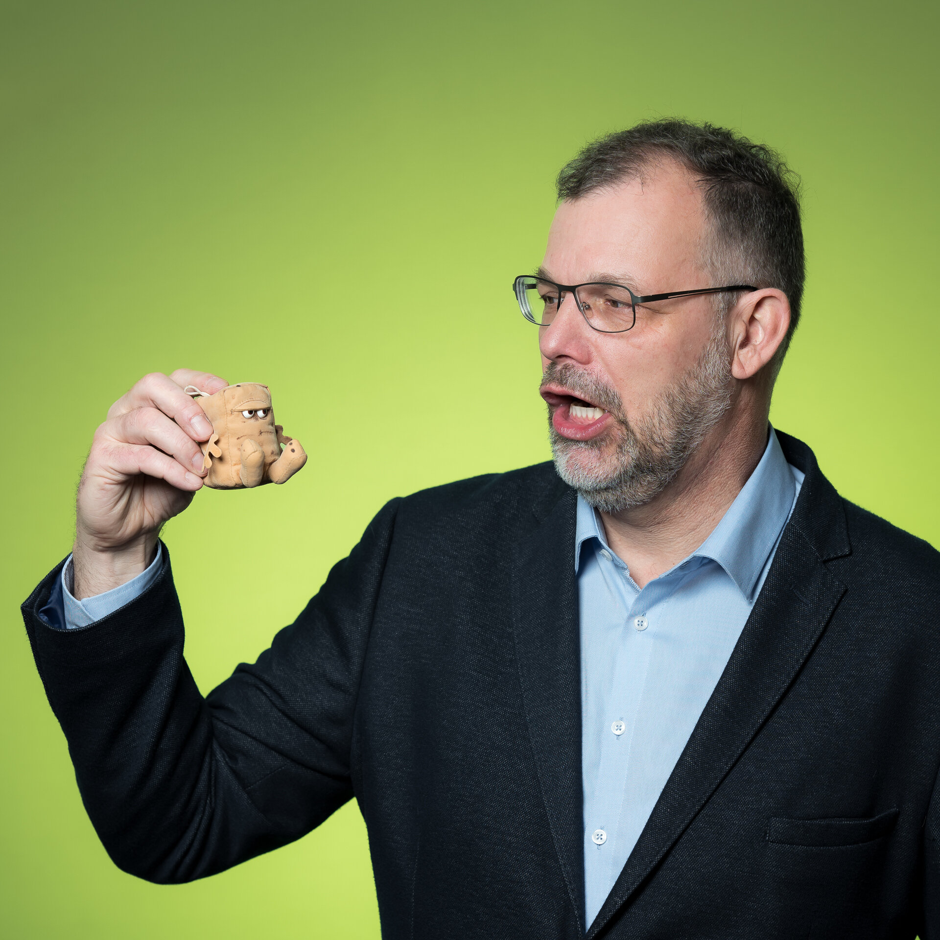 Bernd Brückmann redet mit dem Stofftier "Bernd das Brot" und hält es dabei in der Hand. | © Bamboo Health Care GmbH