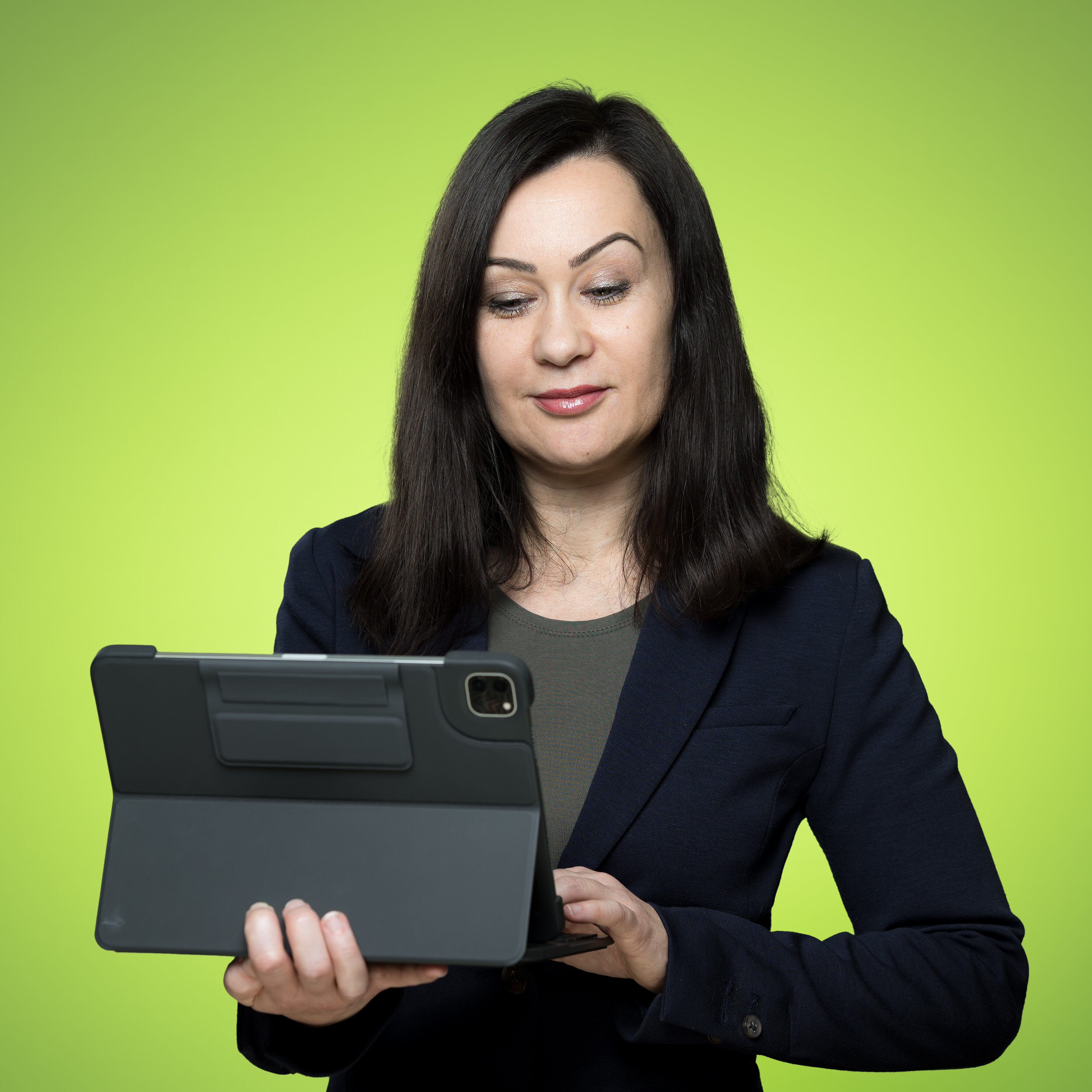 Katharina Model hält ein Tablet auf dem rechten Unterarm, tippt mit der anderen Hand und schaut auf den Bildschirm. | © Bamboo Health Care GmbH